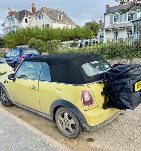 yellow mini convertible in a road with a hatch-bag luggage rack fitted 