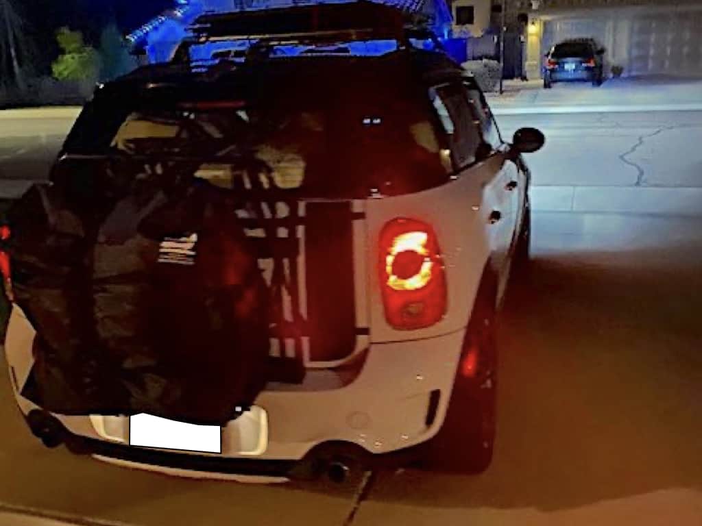 white mini countryman with a roof box fitted at night on a drive lights on